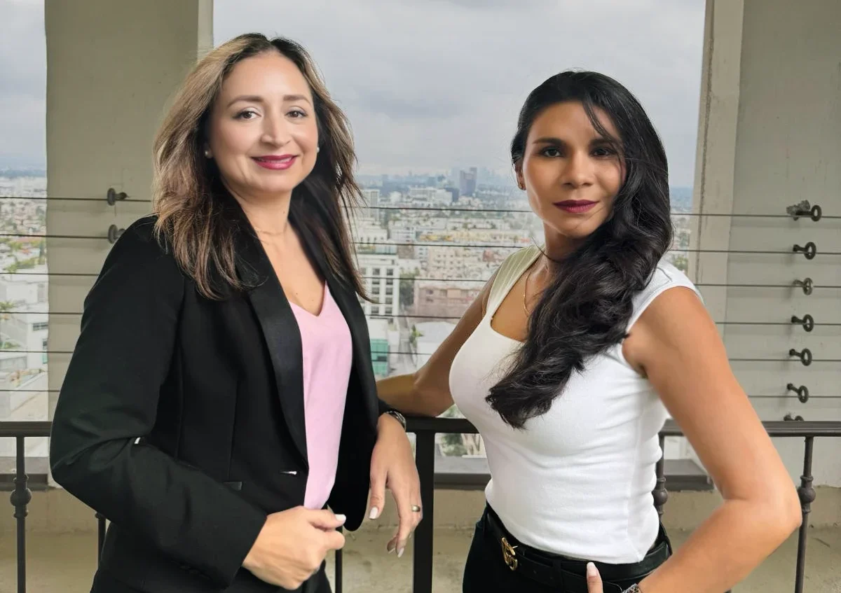 Dos mujeres hispanas de nuestro equipo vestidas formal en un edificio con vista a los angeles.